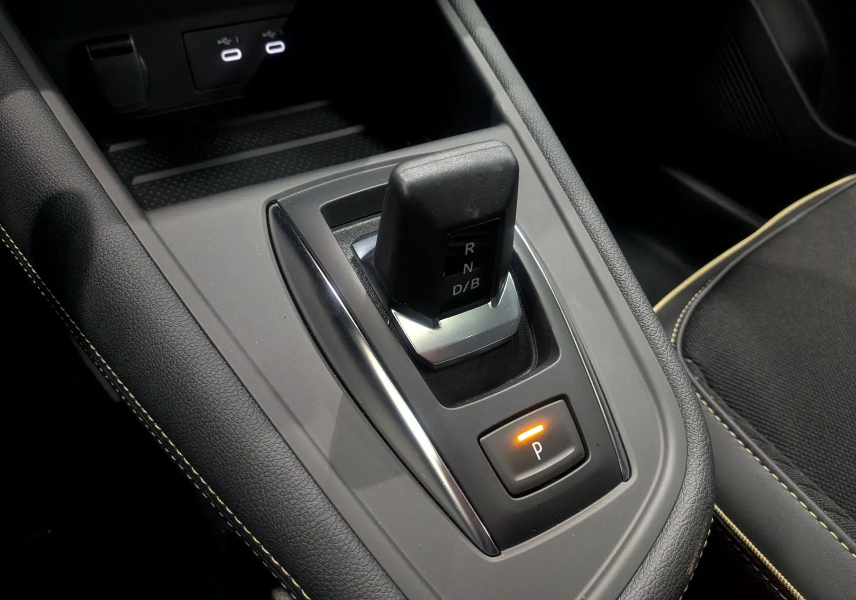 Le levier de vitesses automatique noir de la Renault Symbioz E-Tech, avec bouton de parking éclairé, vue intérieure rapprochée.