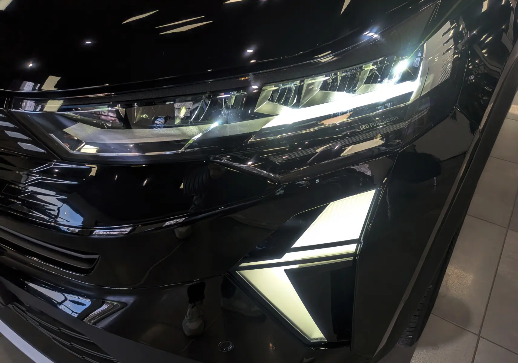 Gros plan sur le phare avant droit du Renault SYMBIOZ noir étoilé avec éclairage LED distinctif allumé.