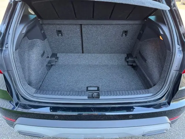 Coffre ouvert vu de l'arrière d'un SEAT Arona noir toit gris, montrant un espace de chargement vide et bien fini.