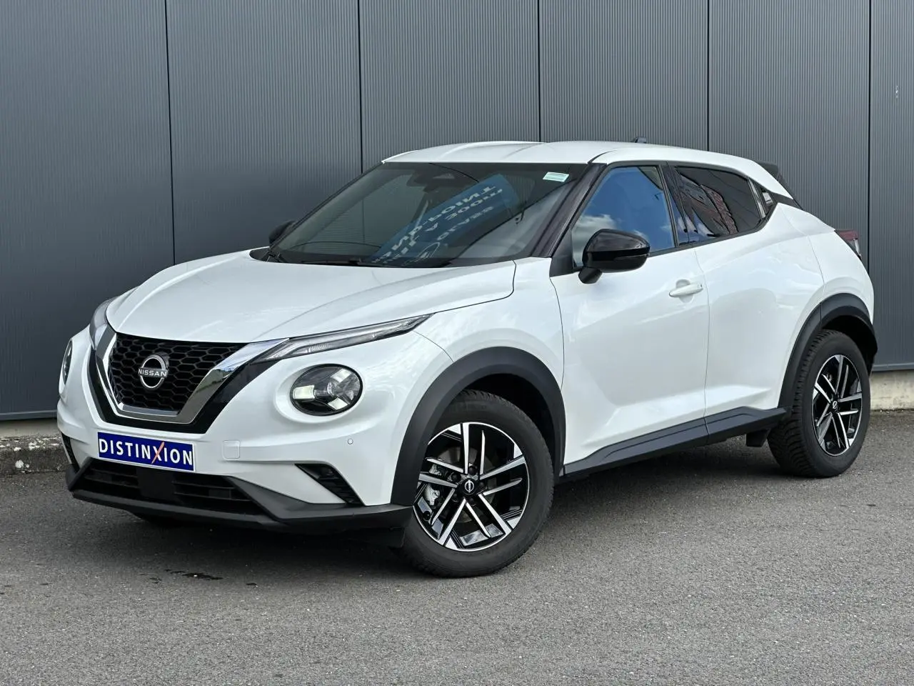 Nissan Juke blanc nacré en 3/4 avant droit, avec jantes alliage noires et détails noirs contrastants.
