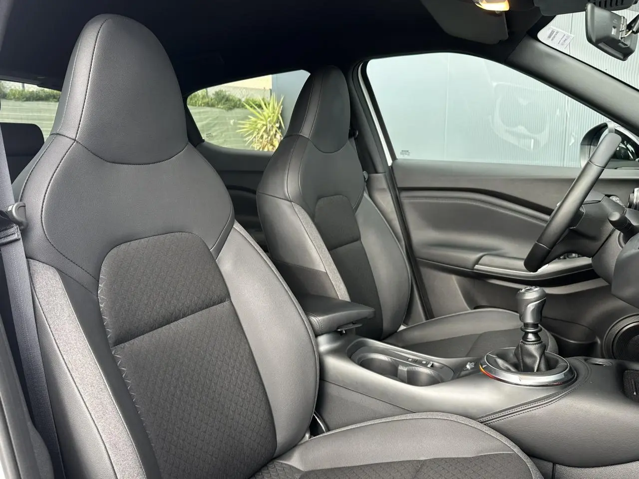 Vue intérieure côté droit du Nissan Juke 2025 N-Connecta, sièges noirs et levier de vitesse manuel visibles.