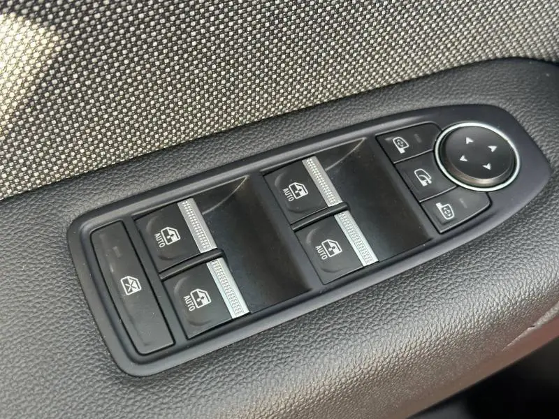 Gros plan sur les commandes des vitres électriques et des rétroviseurs côté gauche intérieur du Renault Captur Rouge Flamme/Noir Étoilé 2025.