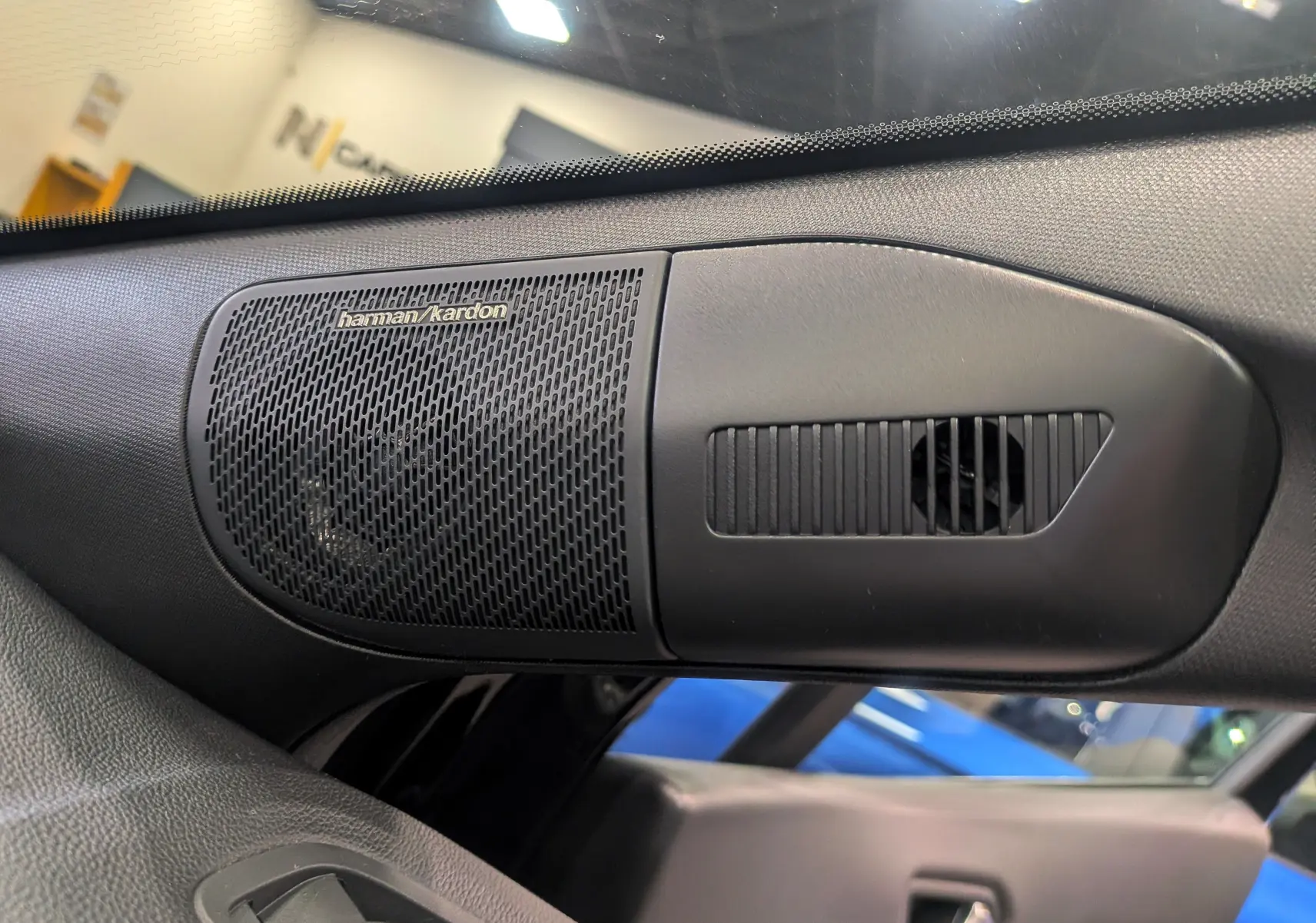 Gros plan sur l'enceinte Harman Kardon intégrée dans la porte côté gauche de la Renault Symbioz E-Tech noir étoilé.