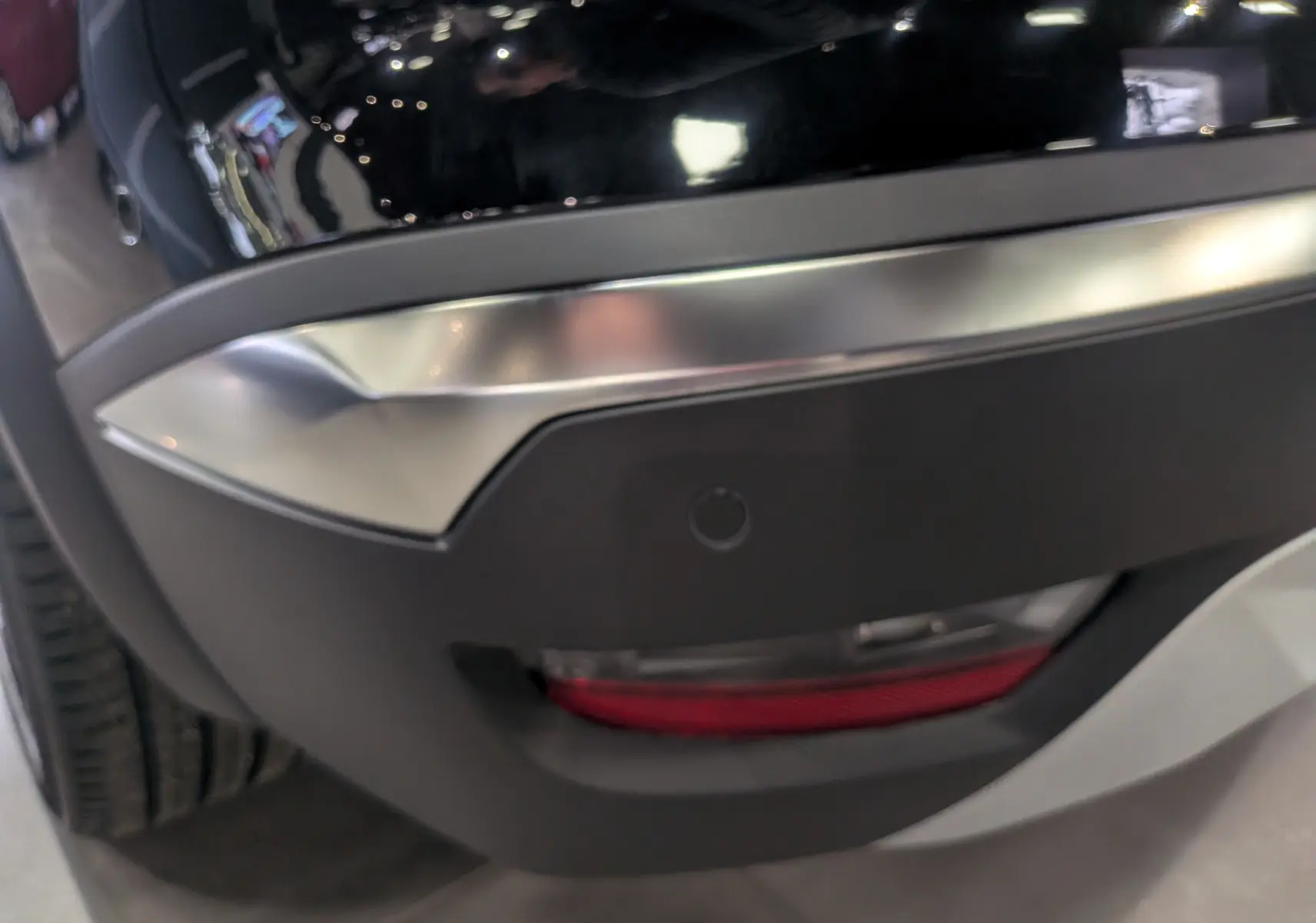 Gros plan sur le pare-chocs arrière droit noir étoilé du Renault Symbioz E-Tech 160 ch avec un feu rouge intégré.