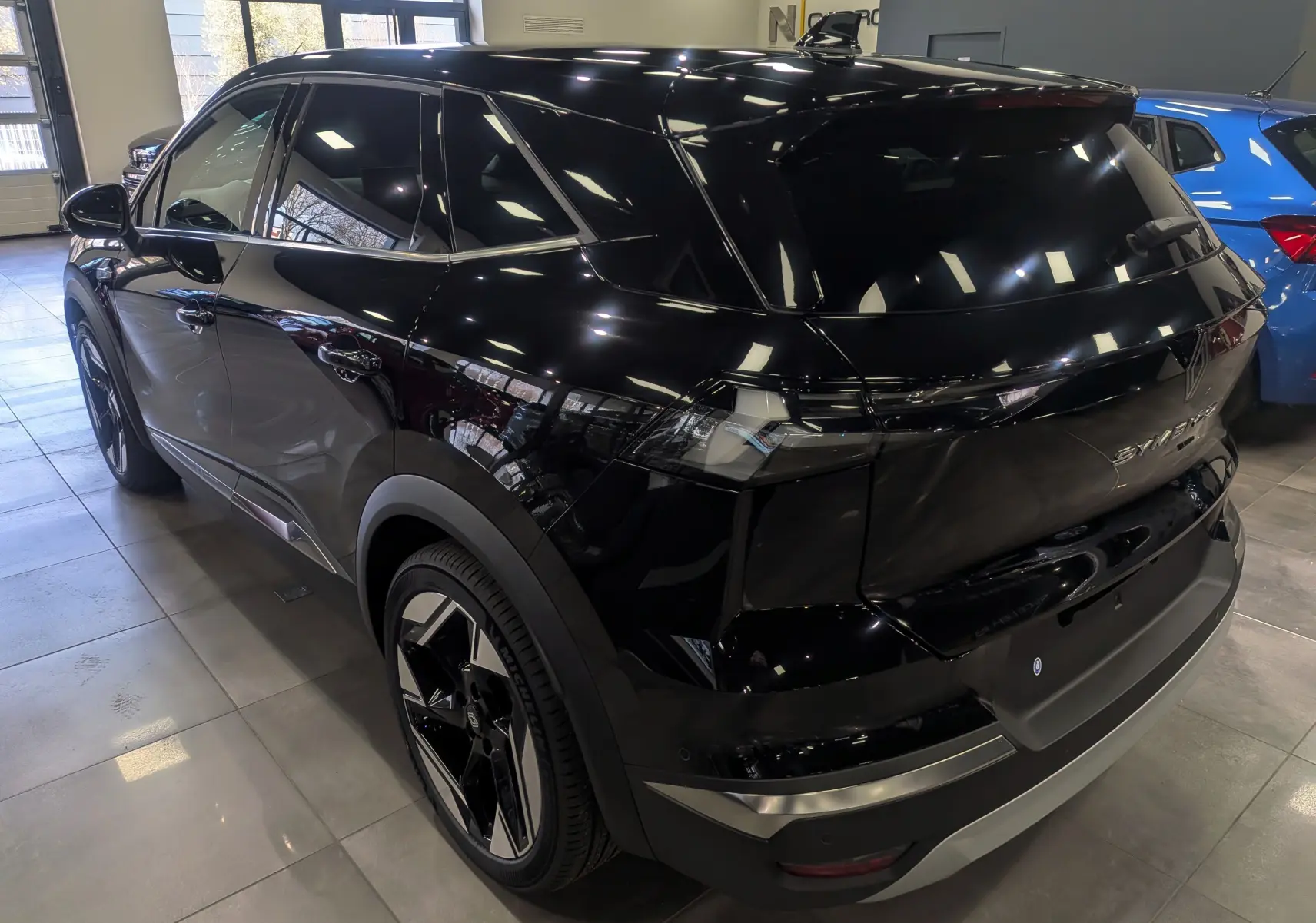 Vue 3/4 arrière droite du Renault SYMBIOZ noir étoilé, soulignant ses lignes modernes et ses jantes bicolores distinctives.