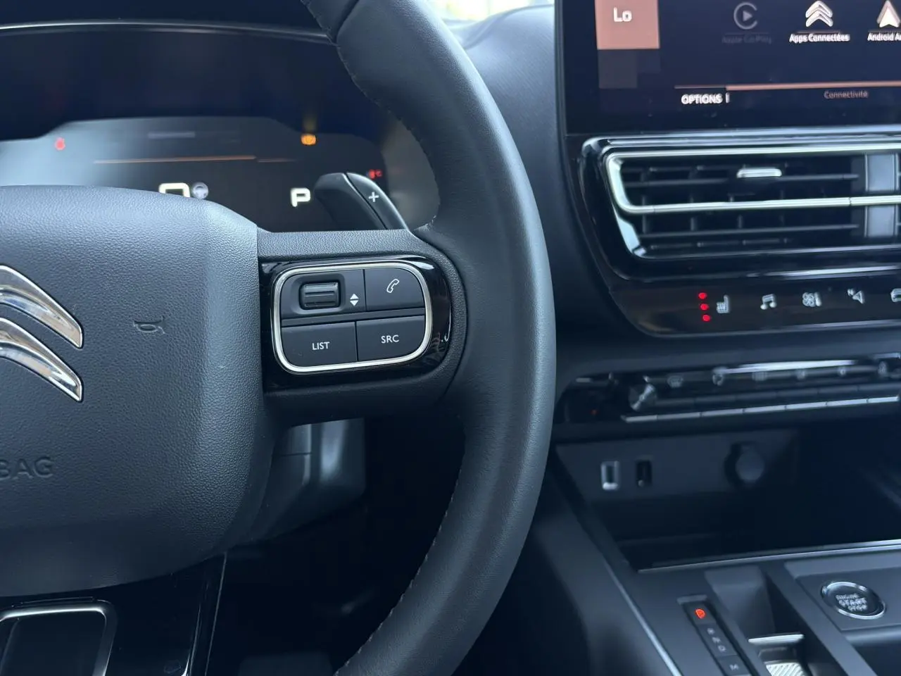 Gros plan sur le volant noir et la console centrale du Citroën C5 Aircross Hybrid 2025 avec commandes intégrées et écran tactile.