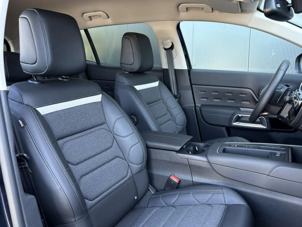 Vue intérieure côté avant droit du Citroën C5 Aircross Hybrid 2025, sièges Advanced Comfort en cuir et tissu gris foncé.