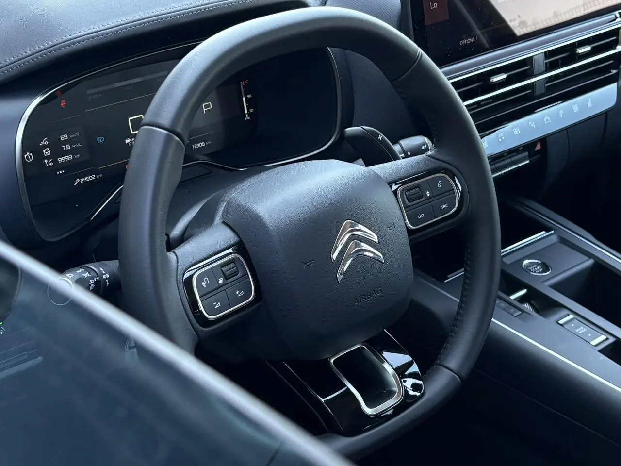Vue rapprochée du volant en cuir noir et du tableau de bord numérique du Citroën C5 Aircross Hybrid 2025.