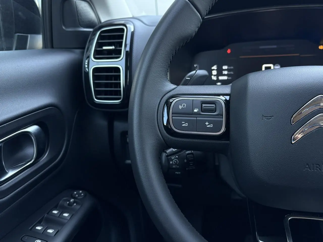 Détail du volant et tableau de bord noir du Citroën C5 Aircross Hybrid 2025, avec commandes intégrées au volant.