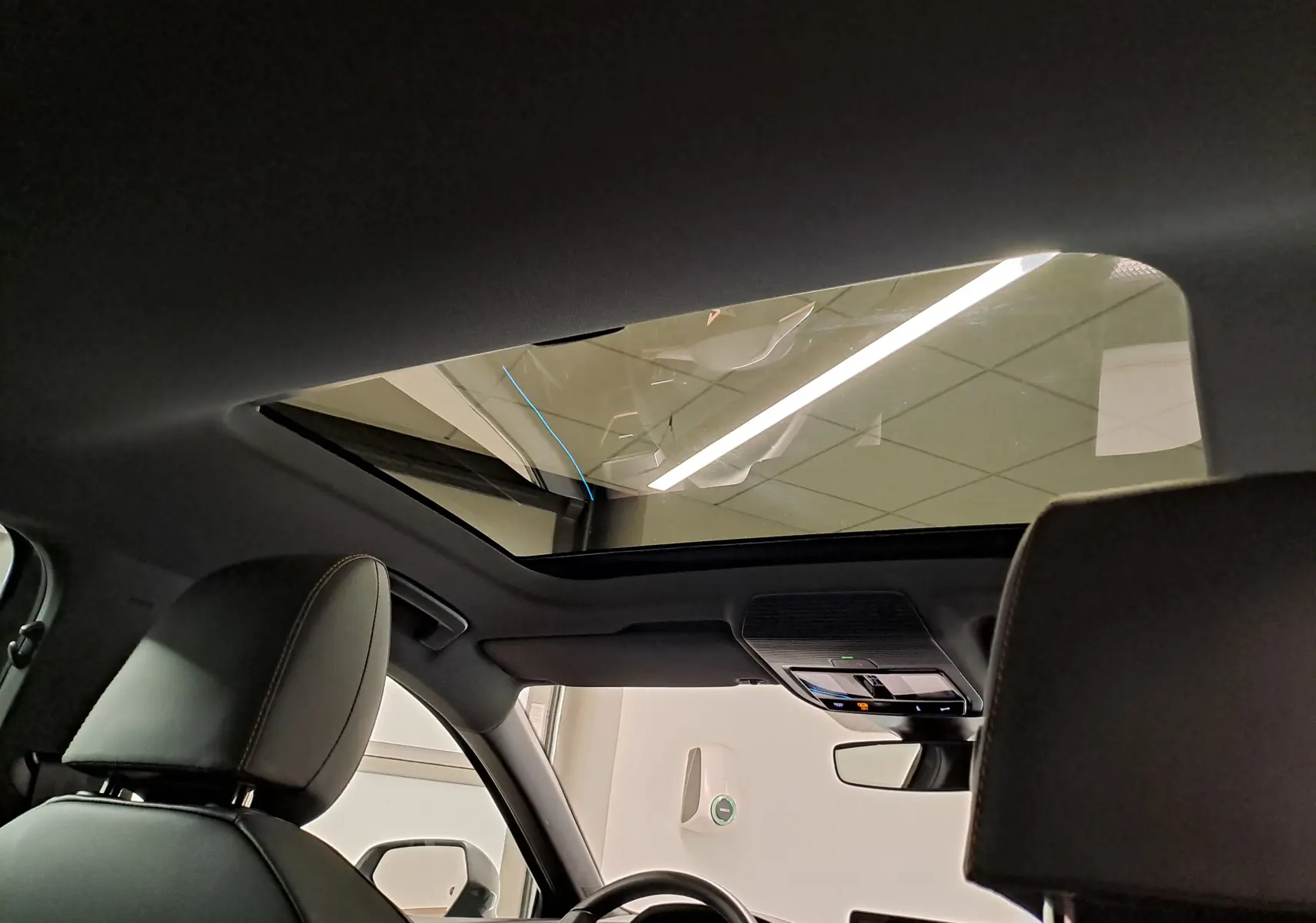 Vue intérieure du toit ouvrant panoramique du CUPRA Leon 2025, avec sièges avant en cuir et console de toit visible.