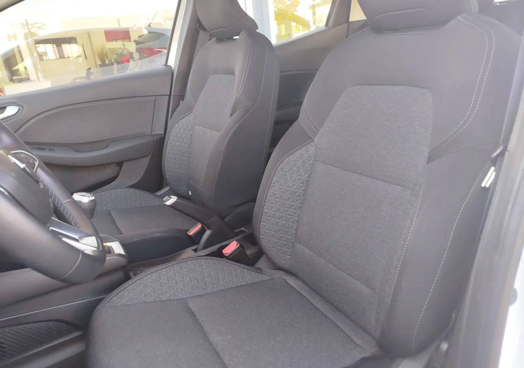 Vue intérieure côté droit des sièges avant en tissu gris foncé de la Renault Clio Business blanche de 2021.