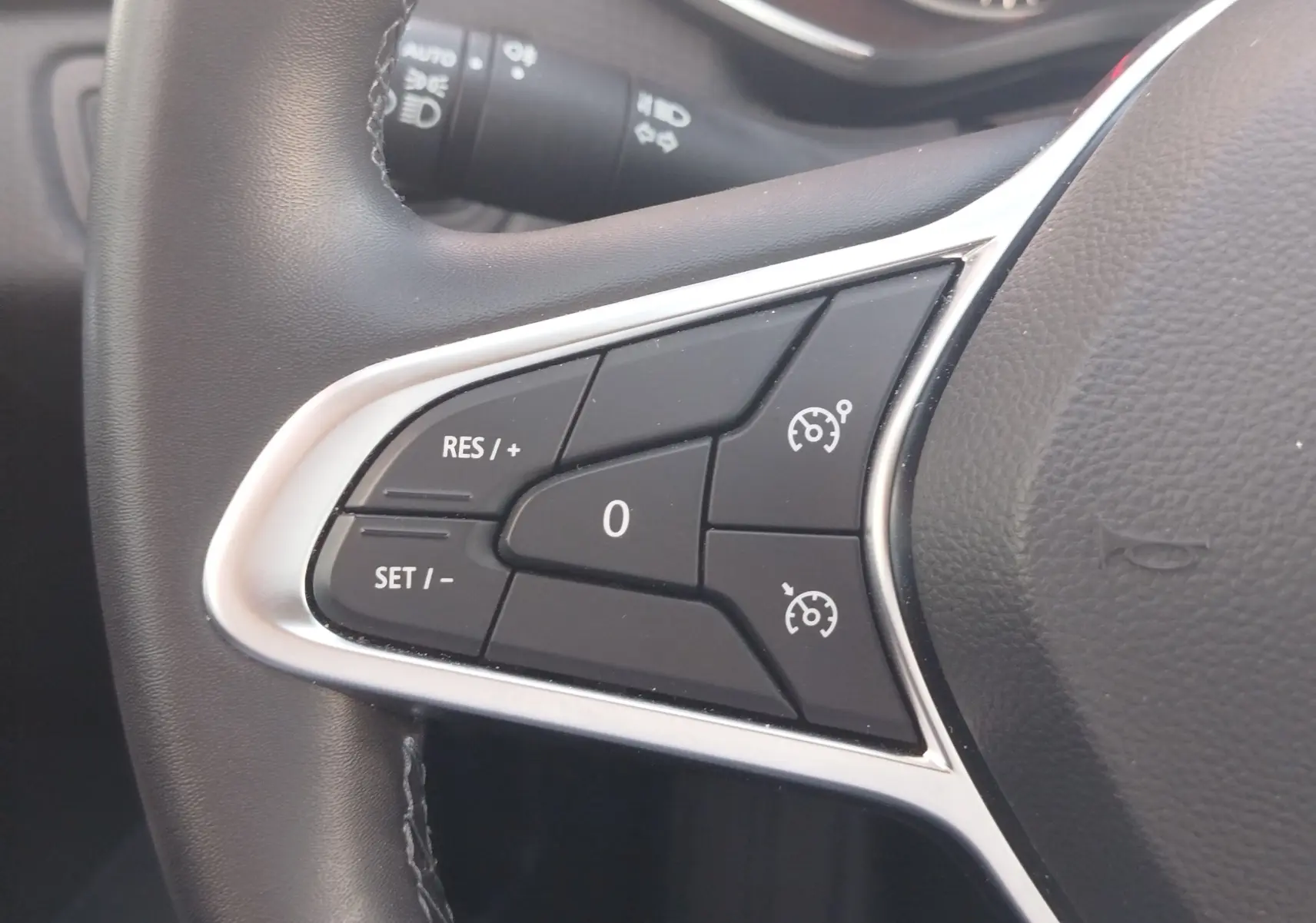 Gros plan sur les commandes de régulateur de vitesse au volant noir de la Renault Clio Business blanche 2021.