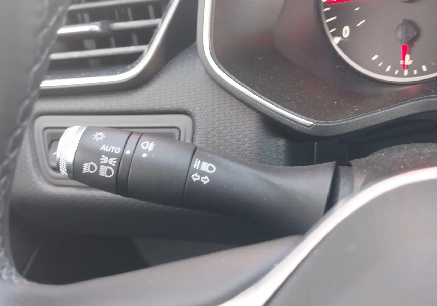 Gros plan sur la commande des phares et clignotants à gauche du volant dans l’habitacle gris d’une Renault Clio blanche 2021.