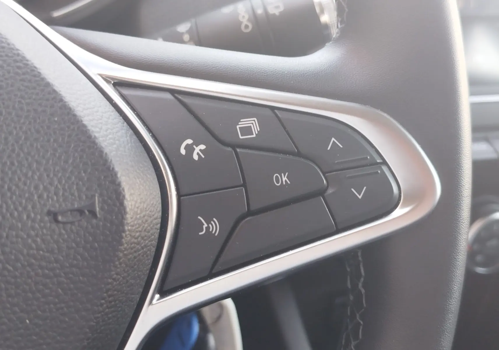 Gros plan sur les commandes multifonctions côté gauche du volant noir de la Renault Clio Business blanche de 2021.