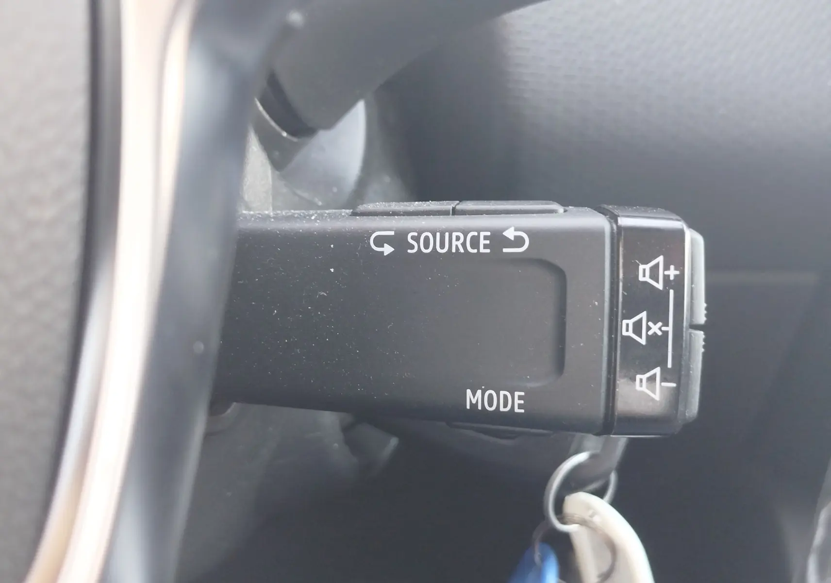 Gros plan sur la commande au volant noire de la Renault Clio blanche 2021, avec boutons source et mode visibles.