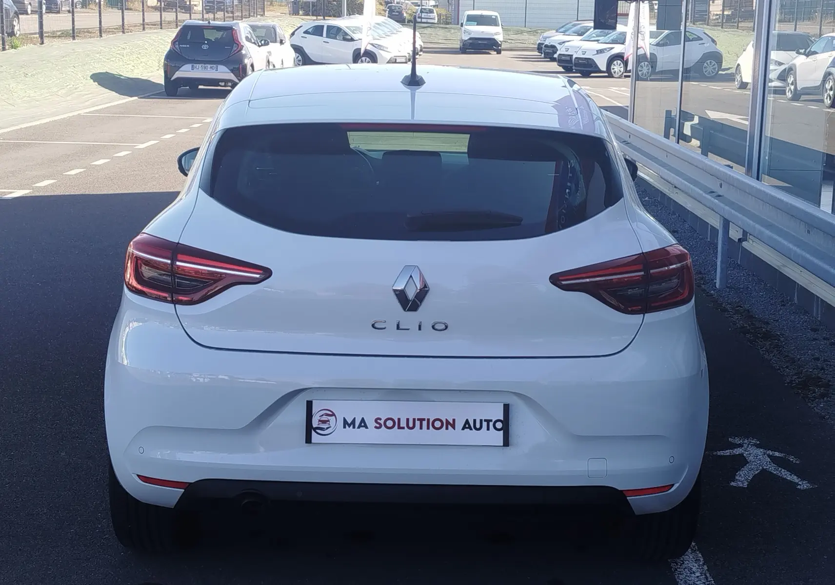 Vue arrière d'une Renault Clio blanche de 2021, mettant en valeur ses feux LED et son logo centré.