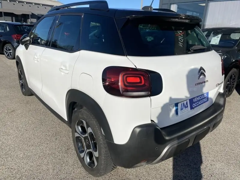 Vue 3/4 arrière droite d'un Citroën C3 Aircross blanc avec toit noir et feux arrière distinctifs en forme de carré.