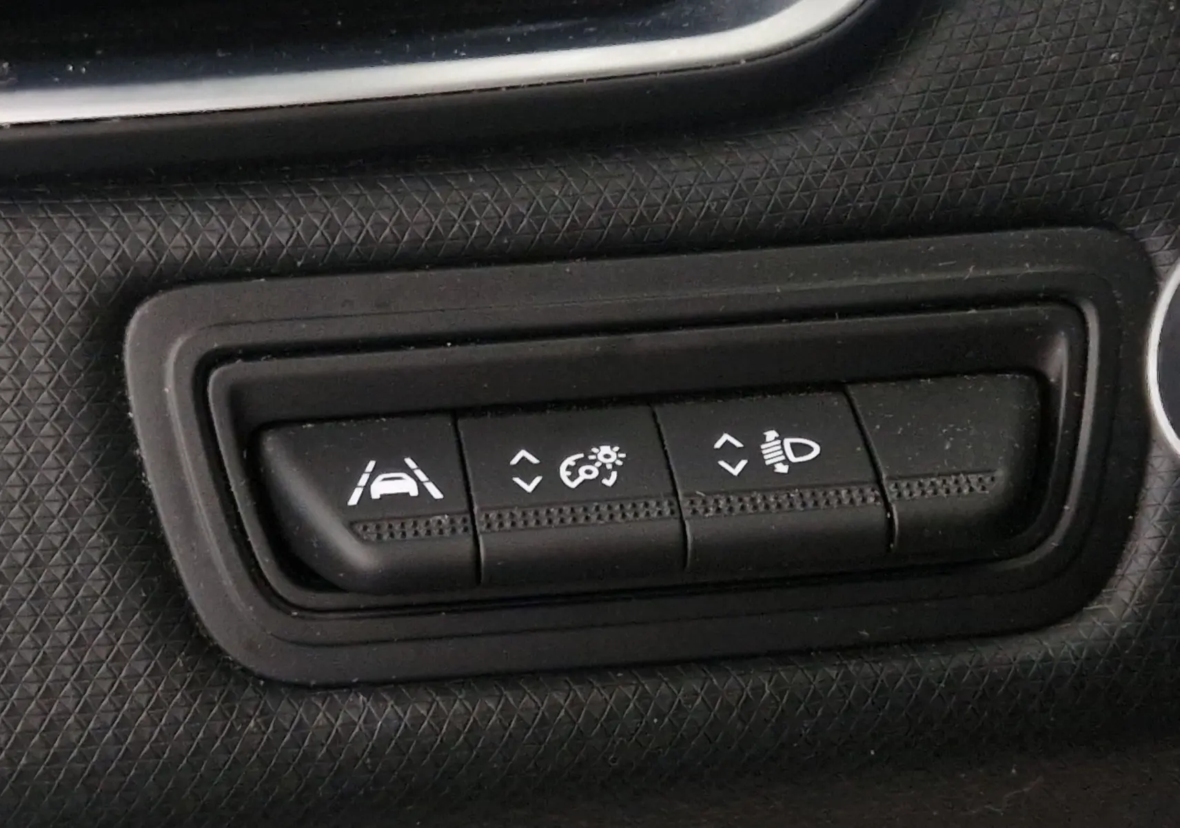 Gros plan sur les boutons de réglage d'assistance et d'éclairage du tableau de bord d'une Renault Clio V gris platine.