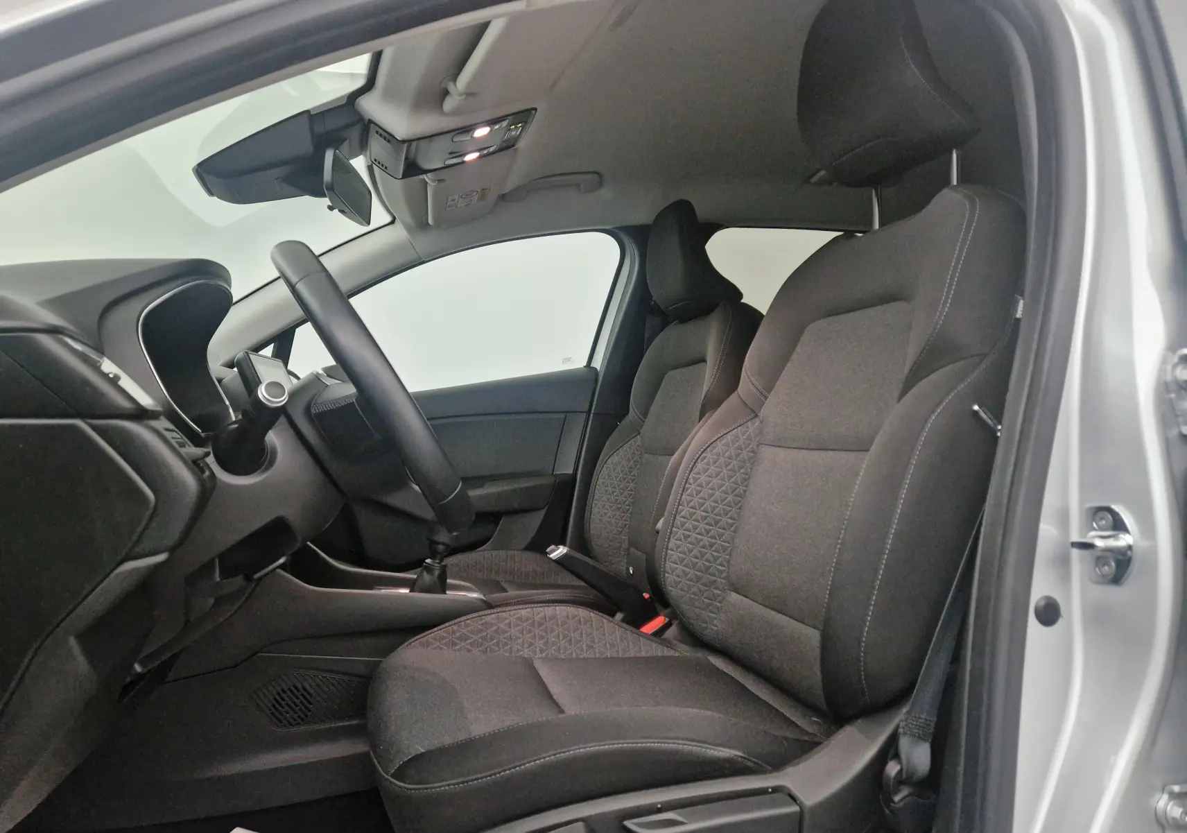 Intérieur avant droit de la Renault Clio V gris platine, sièges tissu noir avec motifs géométriques et volant visible.