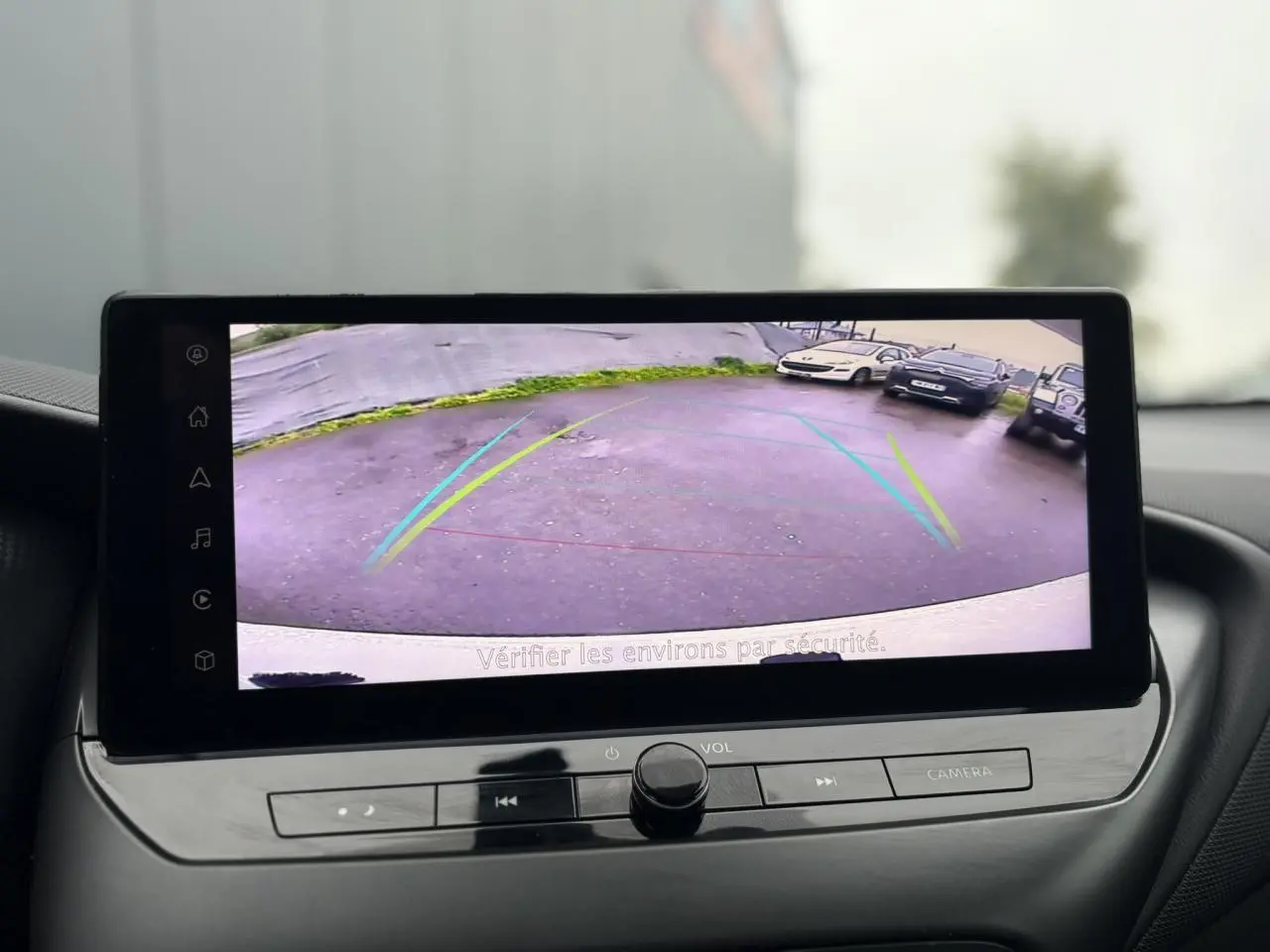 Écran tactile du Nissan Juke 2025 montrant la caméra de recul avec guidage dynamique en intérieur noir.