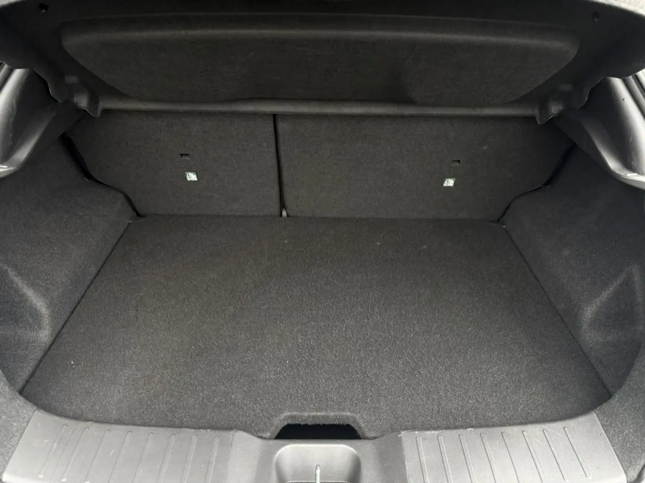 Coffre vide du Nissan Juke blanc nacré, vue intérieure arrière avec banquette rabattable et revêtement gris.