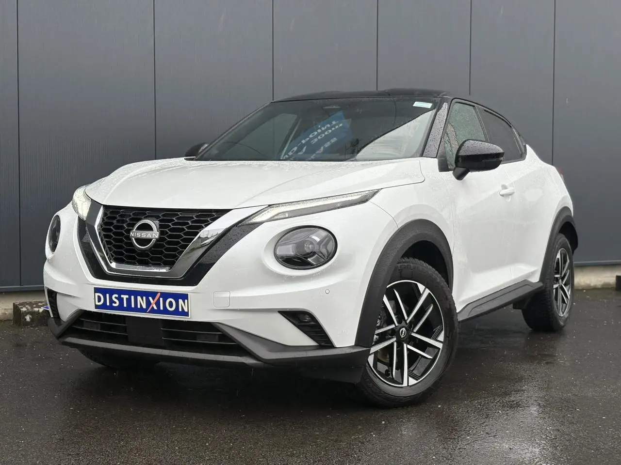 Nissan Juke blanc nacré en 3/4 avant droit, avec toit noir et jantes alliage 17 pouces distinctives.