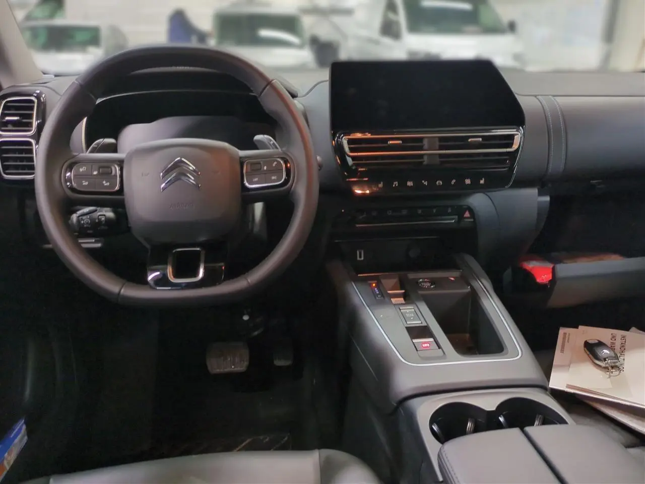 Intérieur noir du Citroën C5 Aircross Hybrid 2025, vue frontale sur volant, écran tactile et console centrale.