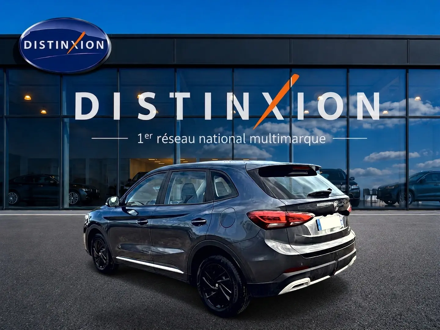 MG ZS 1.5 hybrid Camden grey en 3/4 arrière droit, avec feux LED et jantes noires devant showroom Distinxion.