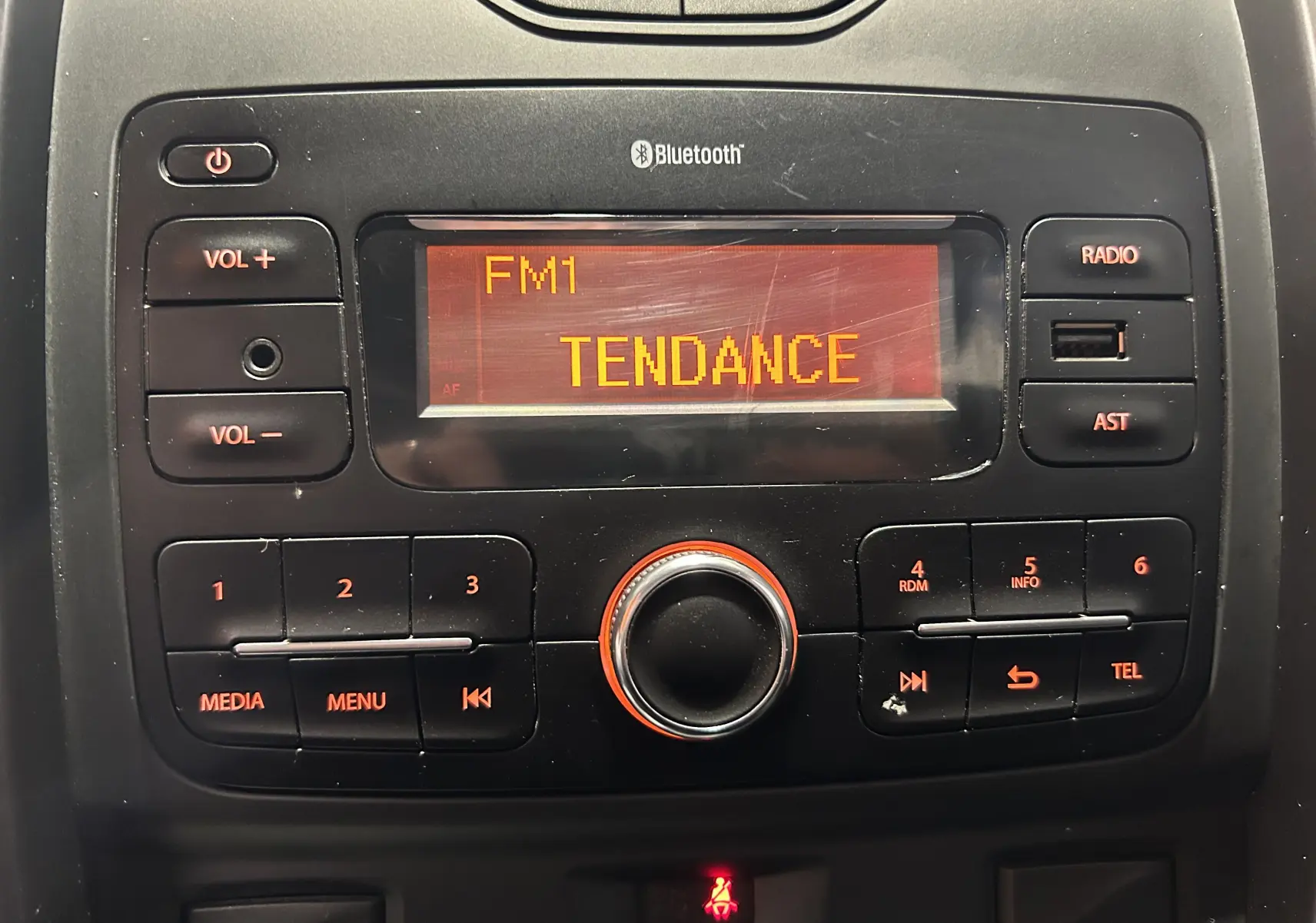 Vue rapprochée de la console centrale du Dacia Duster 2017, affichant la radio FM sur écran orange.