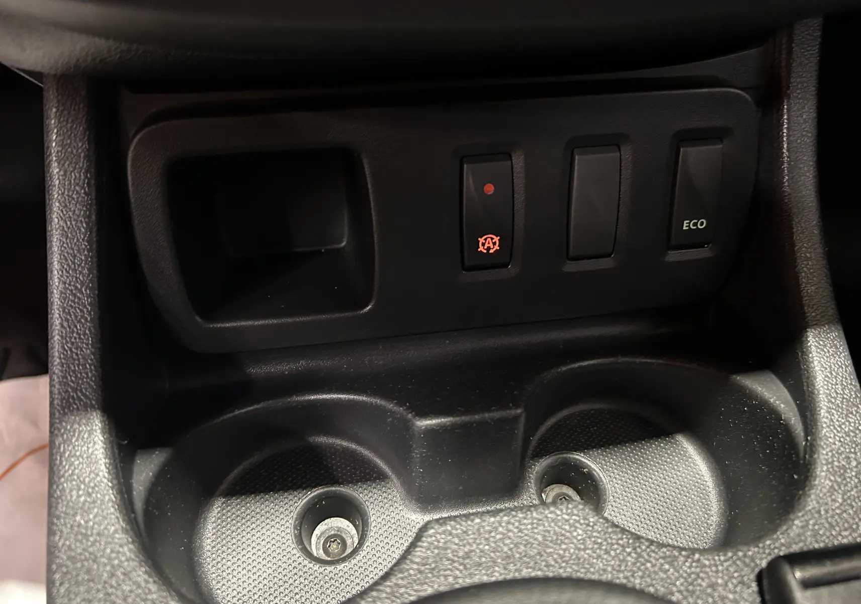 Gros plan sur la console centrale du Dacia Duster gris 2017, montrant les porte-gobelets et les boutons de fonction dont le mode ECO.