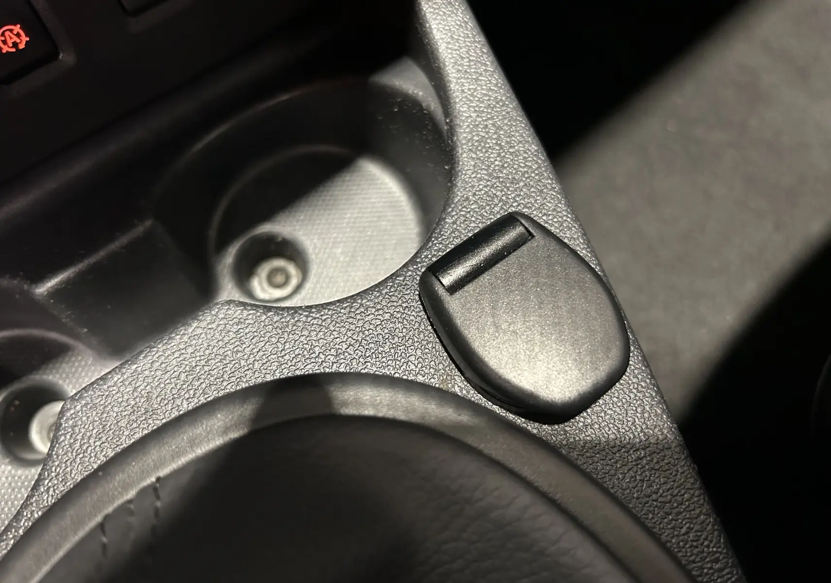 Gros plan sur la console centrale noire du Dacia Duster 2017, mettant en valeur un bouton et un porte-gobelet texturé.