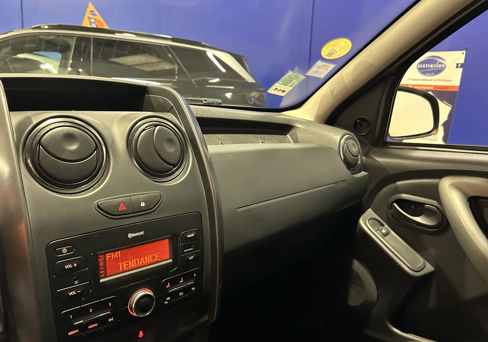 Intérieur du Dacia Duster 2017 gris, vue côté passager sur tableau de bord et console centrale avec radio allumée.
