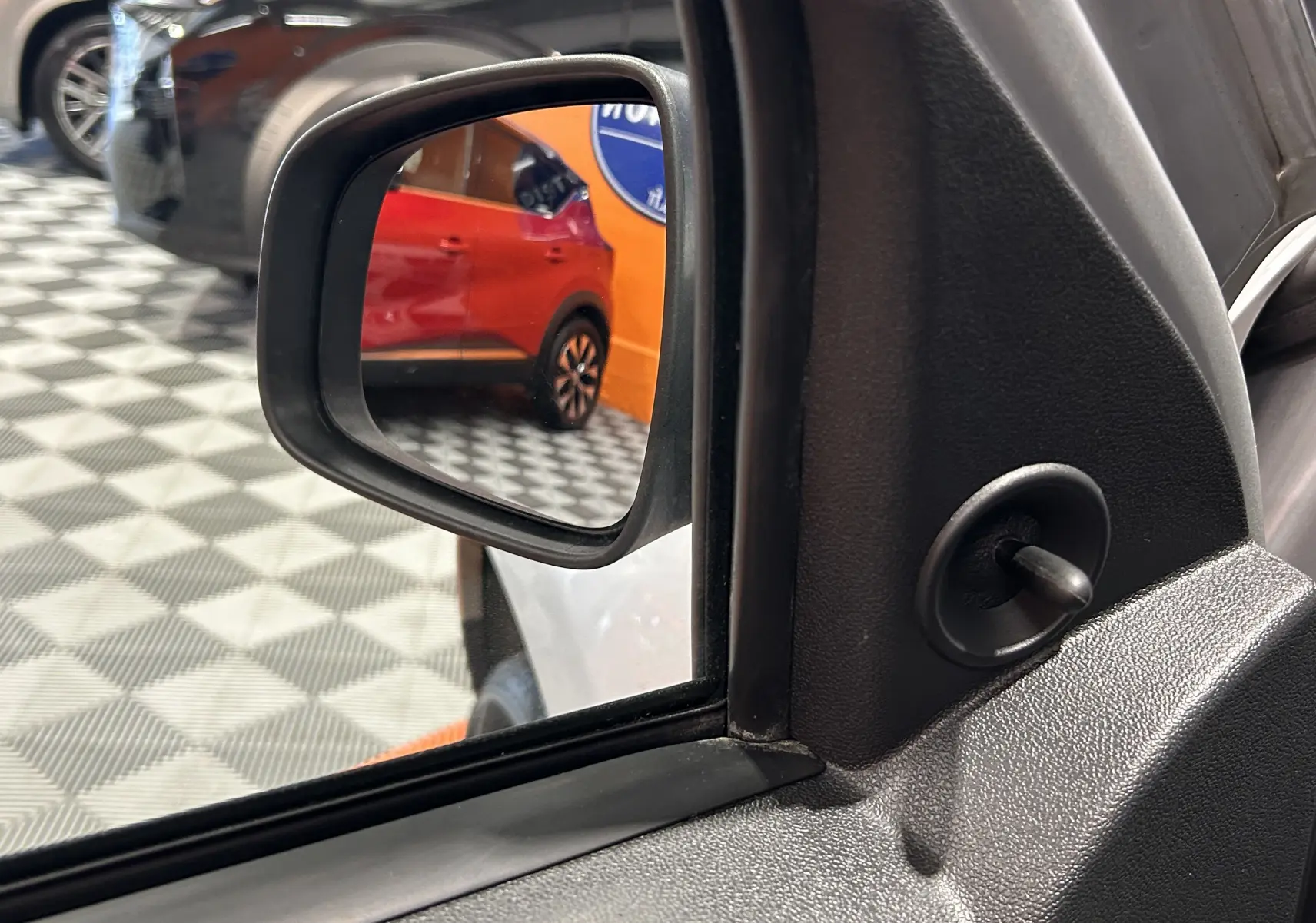 Rétroviseur côté gauche du Dacia Duster gris 2017, avec vue sur un SUV rouge en arrière-plan.