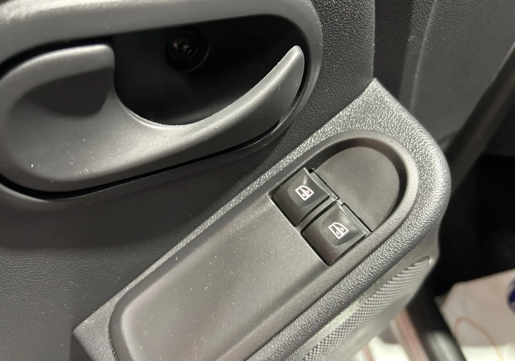 Gros plan sur la commande des vitres électriques côté gauche intérieur du Dacia Duster gris 2017.