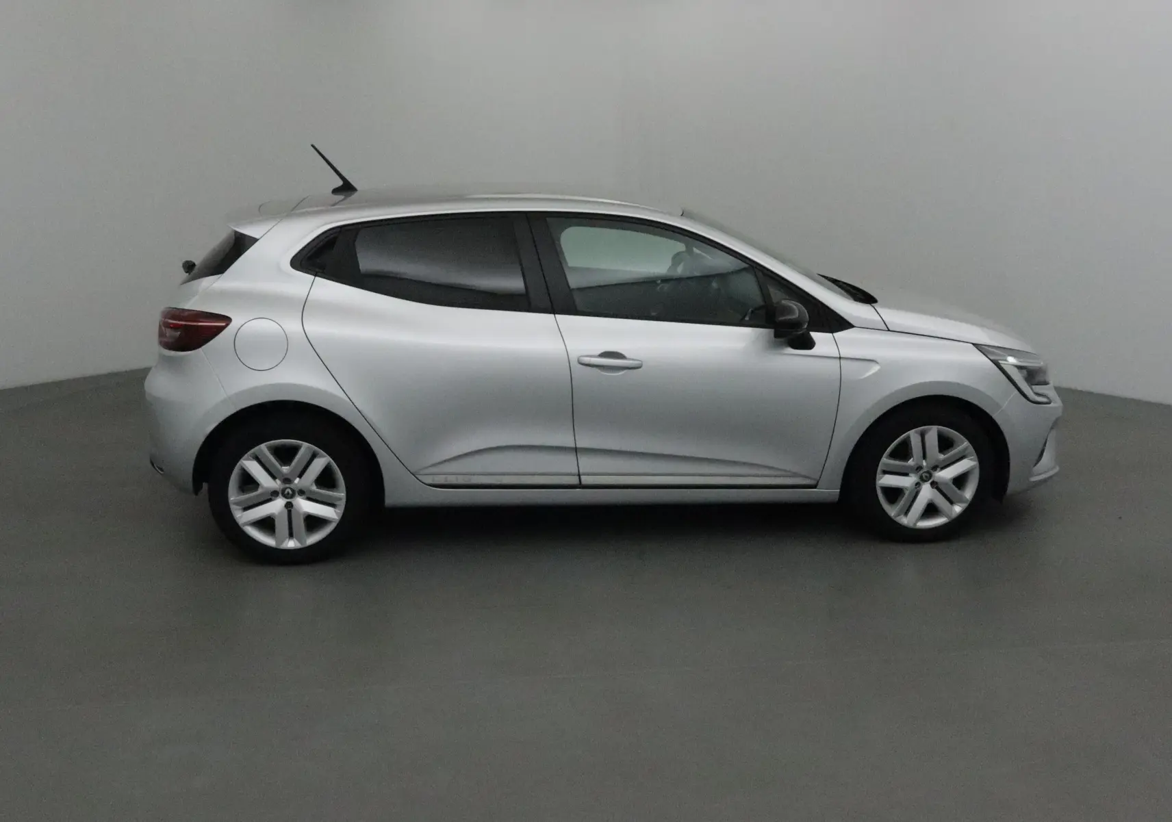 Profil côté gauche d'une Renault Clio V gris platine de 2021, compacte et moderne dans un studio neutre.
