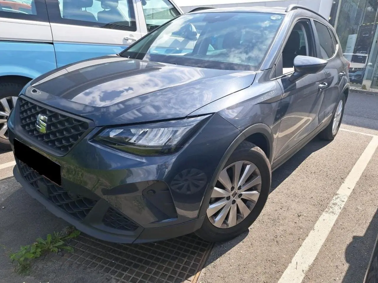SEAT Arona gris magnétique vu en 3/4 avant droit, mettant en valeur ses phares EcoLED et sa calandre distinctive.