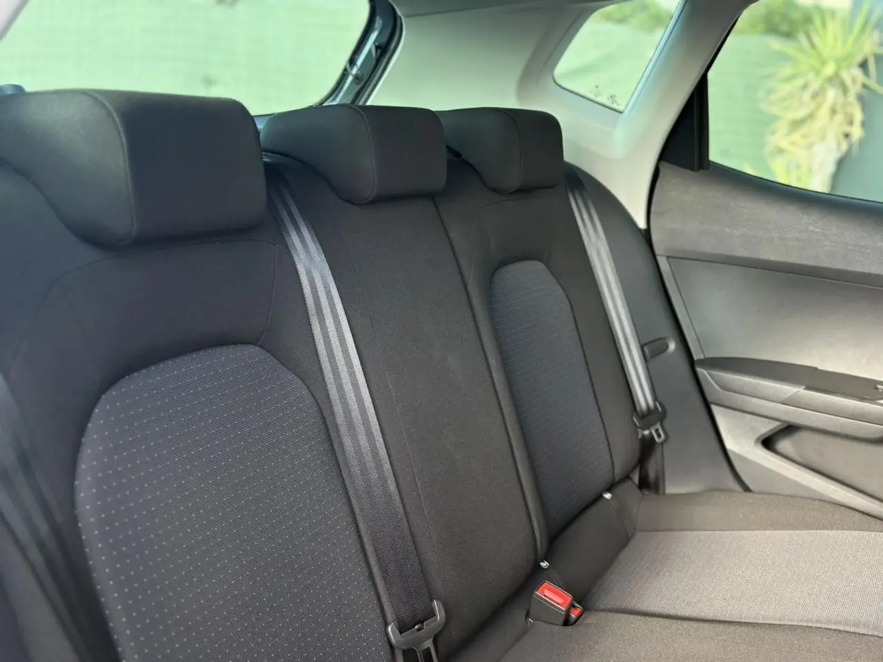 Vue latérale intérieure montrant la banquette arrière noire du SEAT Arona 2024 avec ceintures et appuie-têtes.