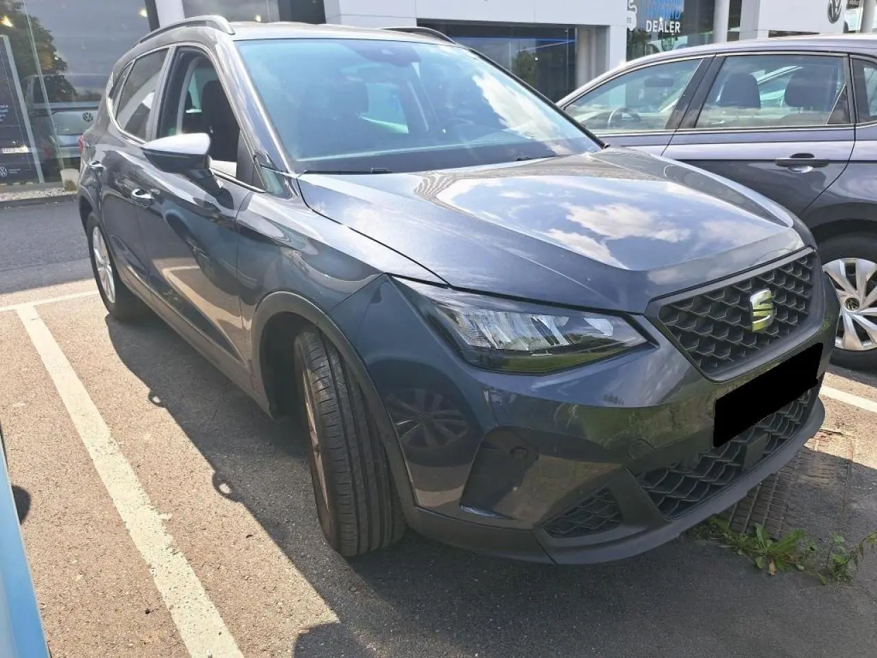 SEAT Arona gris magnétique vue 3/4 avant gauche, avec calandre noire et projecteurs EcoLED visibles.