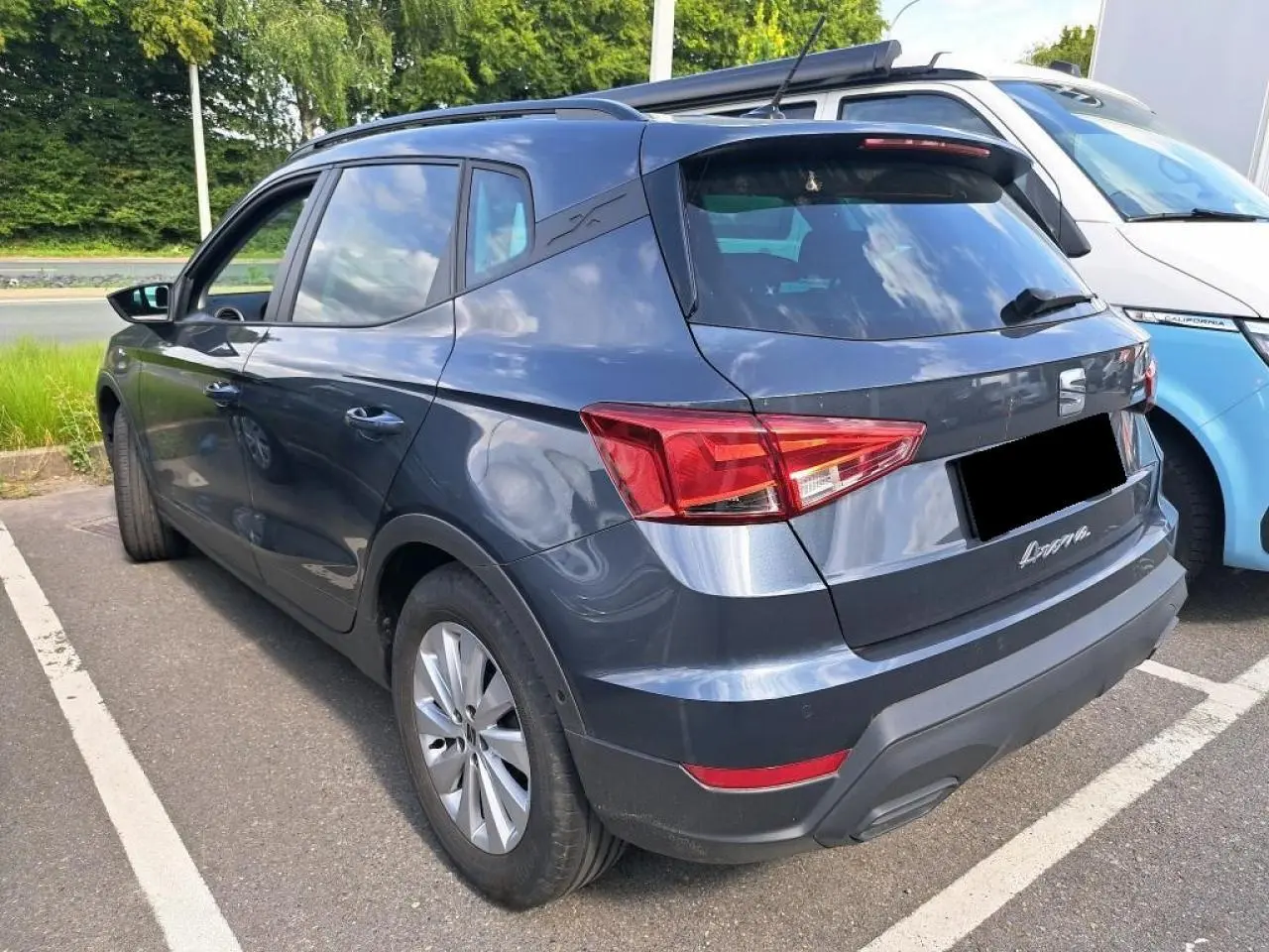 Vue 3/4 arrière gauche d'un SEAT Arona gris magnétique garé, avec feux arrière et jantes alliage visibles.