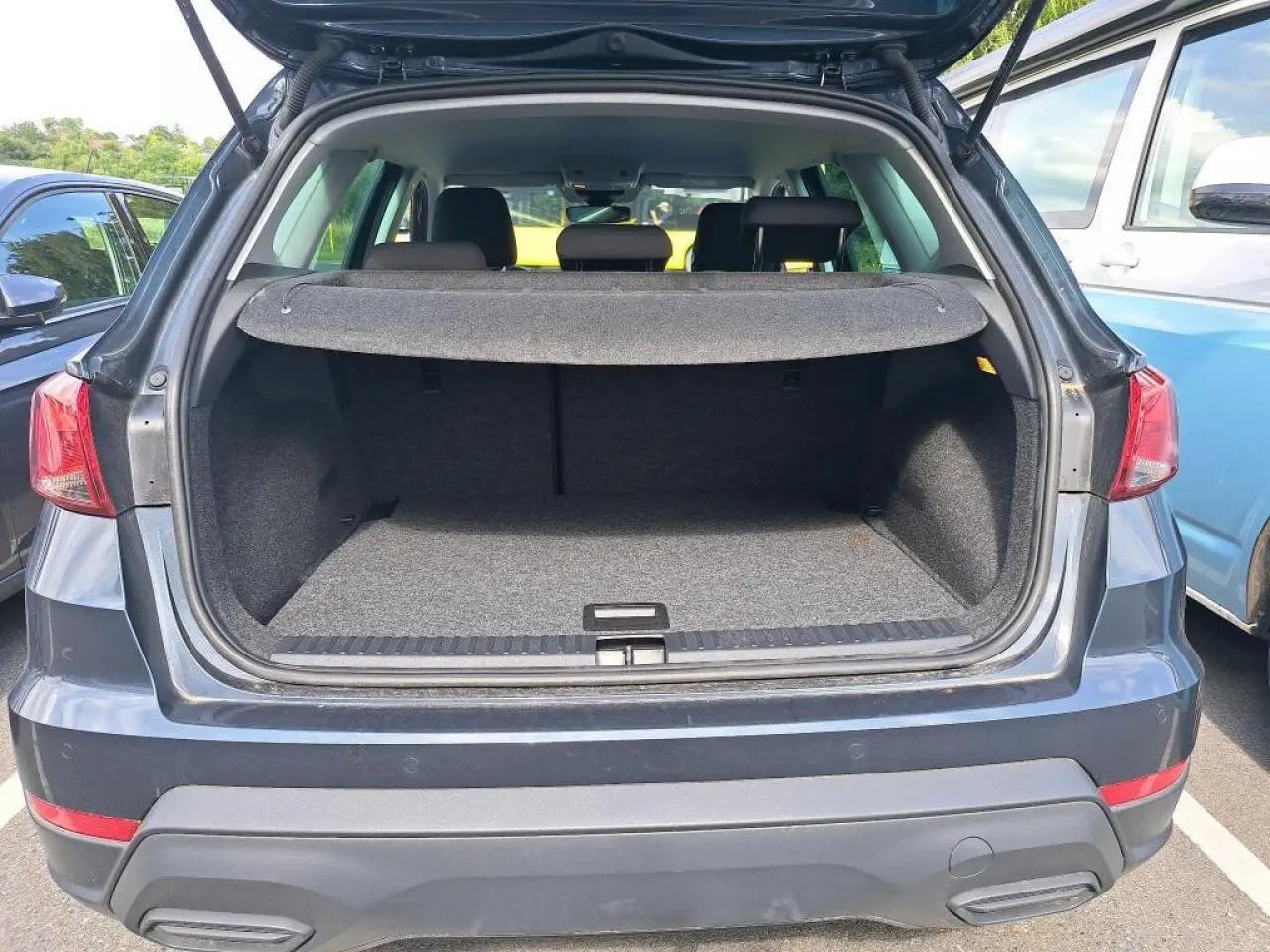 Vue arrière du coffre ouvert du SEAT Arona 2024 gris magnétique, montrant l'espace de chargement vide.