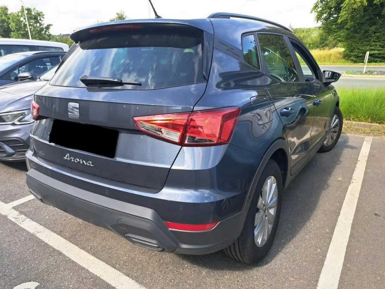 SEAT Arona gris magnétique vue 3/4 arrière droit, avec feux arrière et jantes alliage visibles sur parking.