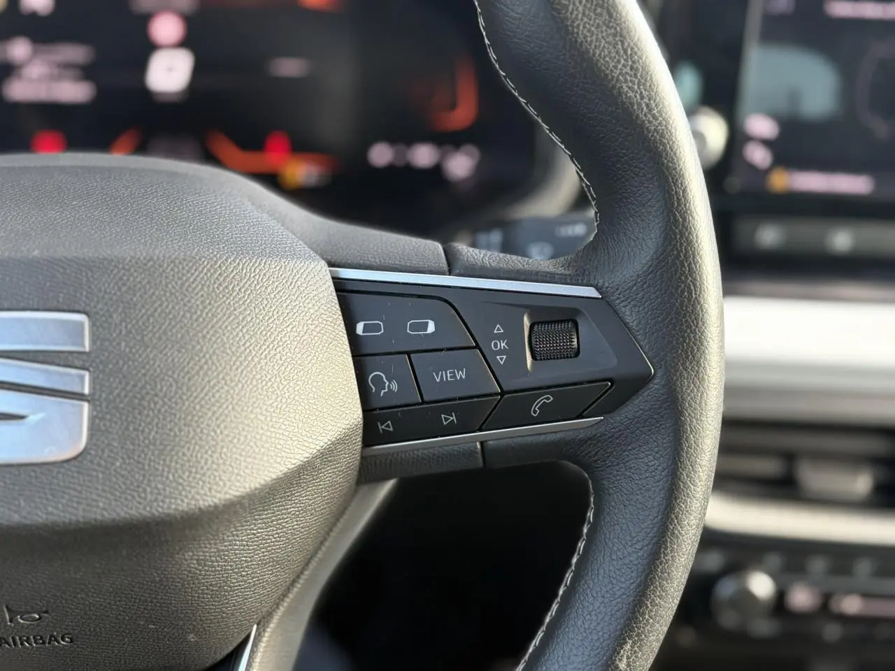 Gros plan sur le volant cuir multifonction droit du SEAT Arona gris avec commandes audio et appel intégrées.