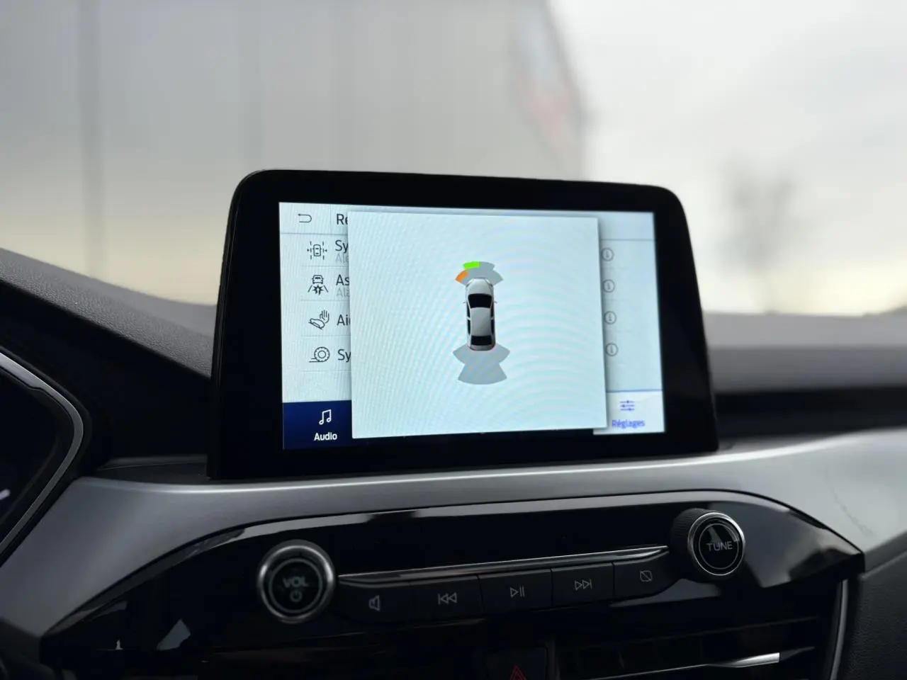 Écran tactile central affichant l’aide au stationnement du Ford Kuga noir Obsidien, vue intérieure du tableau de bord.