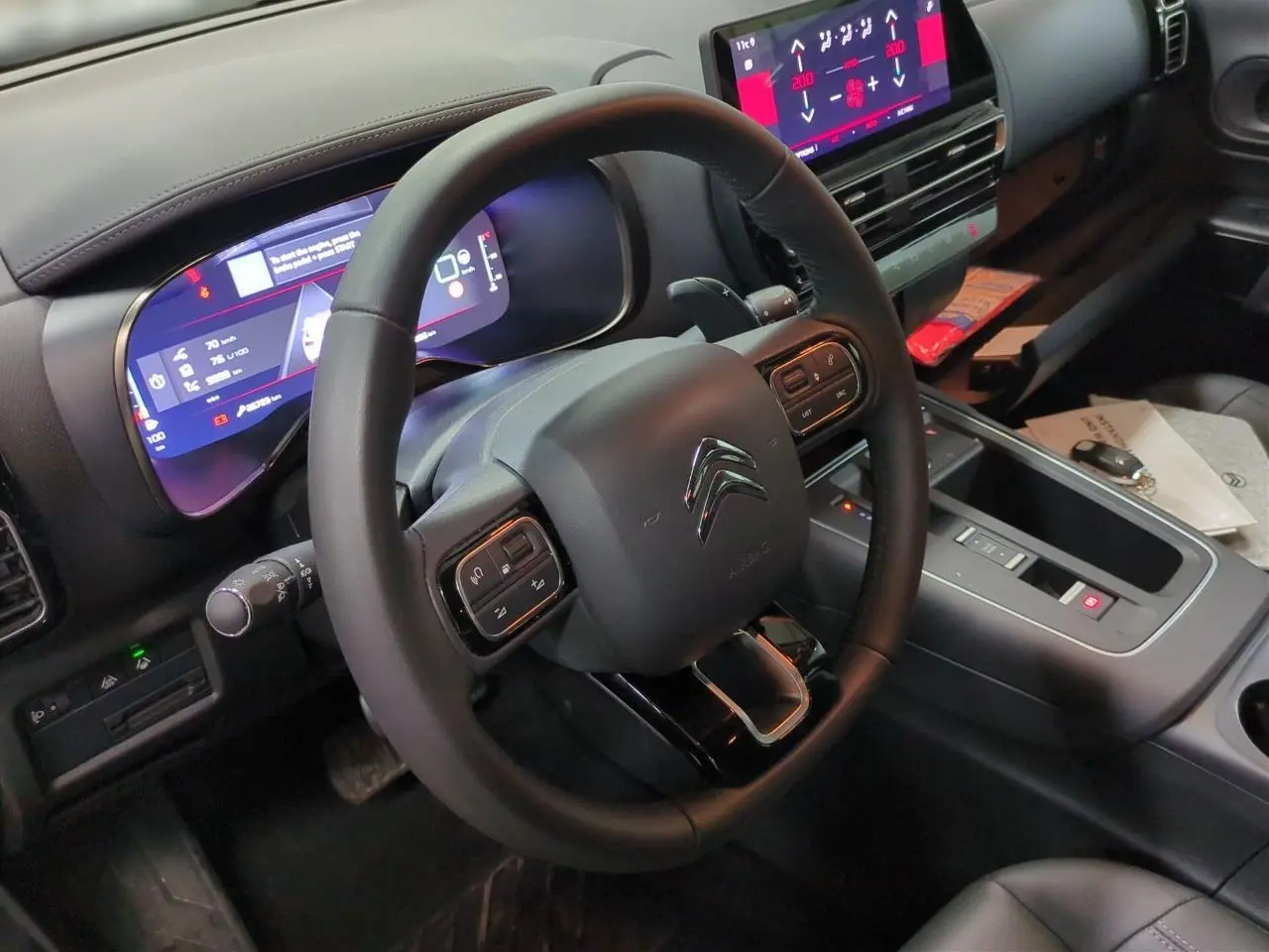 Vue intérieure centrée sur le volant cuir noir et le tableau de bord numérique du Citroën C5 Aircross Hybrid 2025.