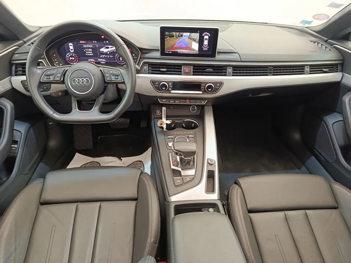Intérieur Audi A5 40 TFSI 2019 vu de face, tableau de bord moderne avec écran central et sièges cuir noirs.