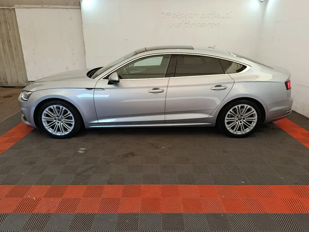 Audi A5 gris clair vue de profil côté gauche, avec jantes alliage et vitres teintées dans un garage.