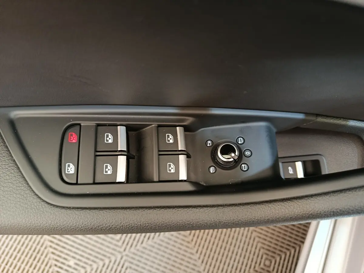 Gros plan sur les commandes de lève-vitres et rétroviseurs côté conducteur d'une Audi A5 gris clair de 2019.