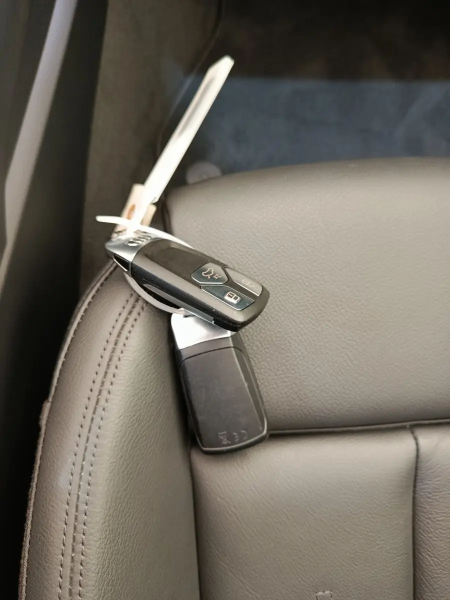 Gros plan sur la clé Audi posée sur un siège en cuir gris clair à l'intérieur du véhicule.