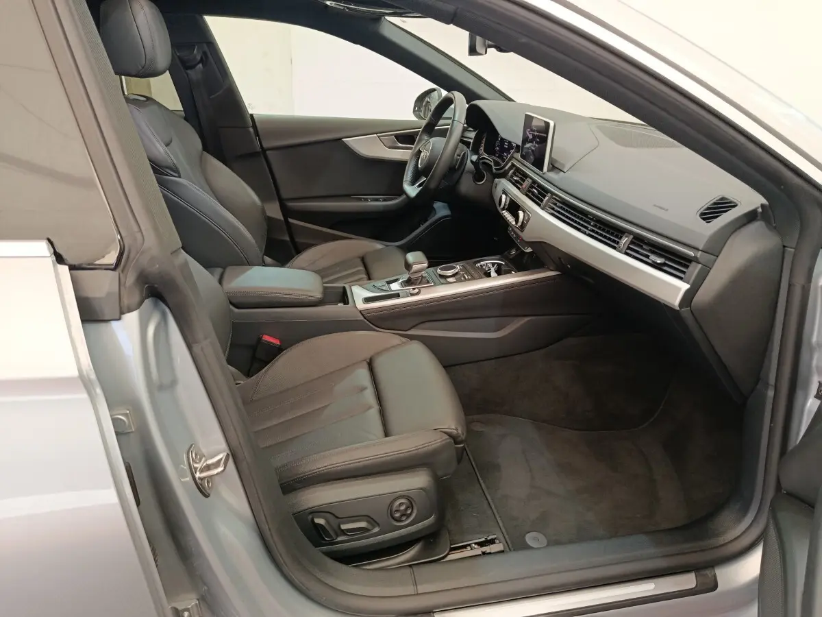 Intérieur côté conducteur d’Audi A5 gris clair, sièges cuir noirs et tableau de bord moderne avec écran central.