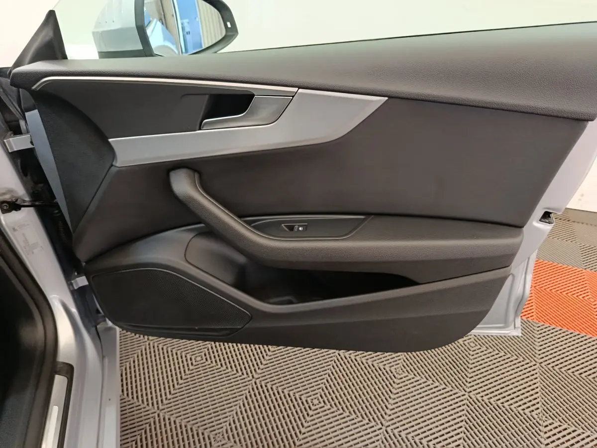 Vue rapprochée de la porte avant gauche de l'Audi A5 gris clair, avec poignée intégrée et commande de vitre.